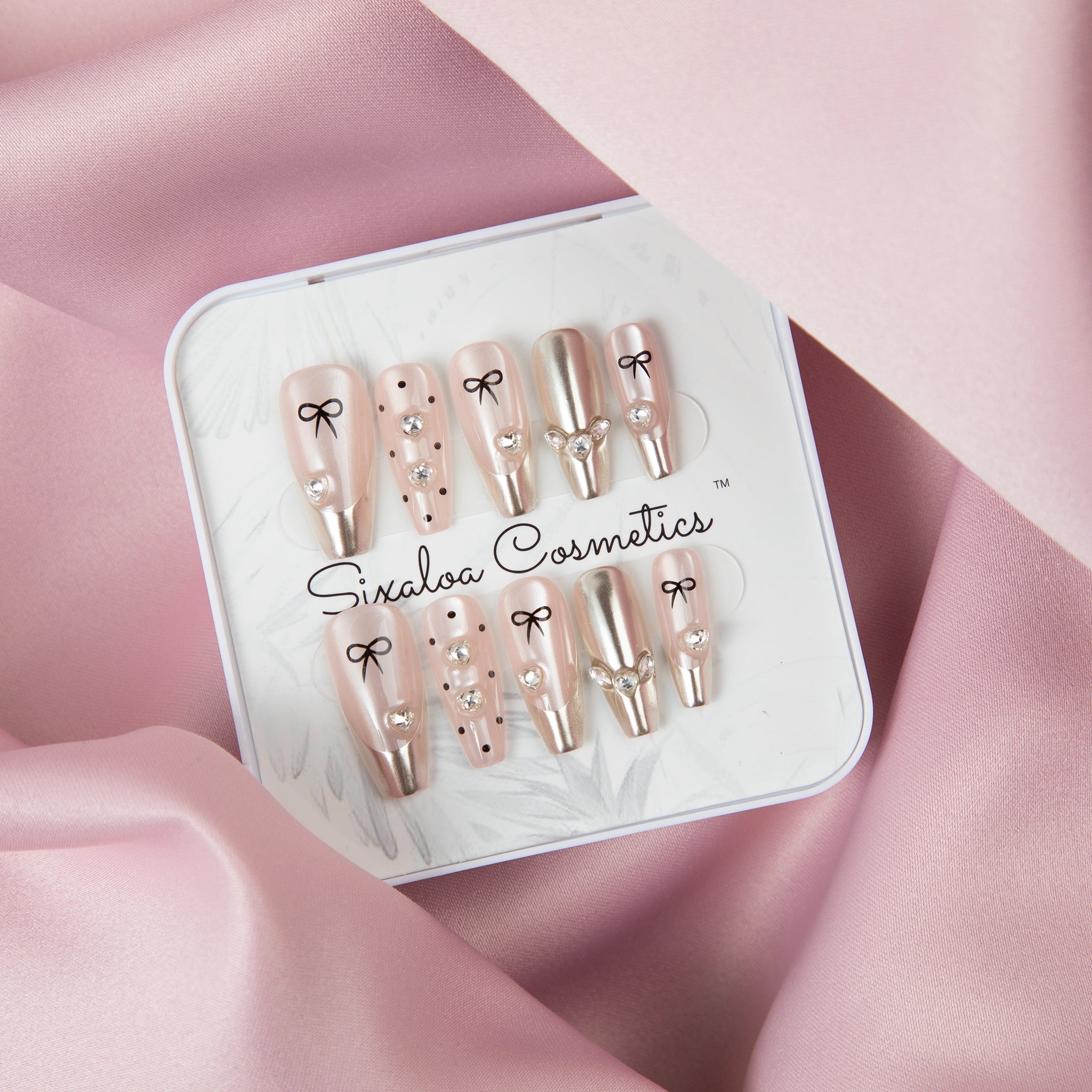 Sixaloa Cosmetics coquette bow press-on nail set in its white keepsake tin on pink satin